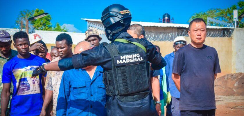 A Man In A Black Uniform With A Crowd Of People Around Him